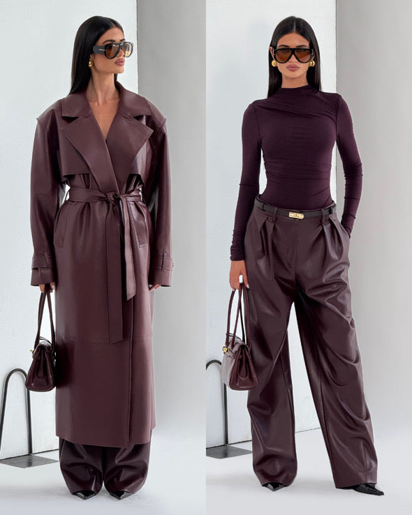 Completo ANITA elegante in eco-pelle nera composto da cappotto lungo con cintura e pantaloni a vita alta dal taglio ampio. Un look deciso e sofisticato, perfetto per chi ama uno stile contemporaneo e audace.