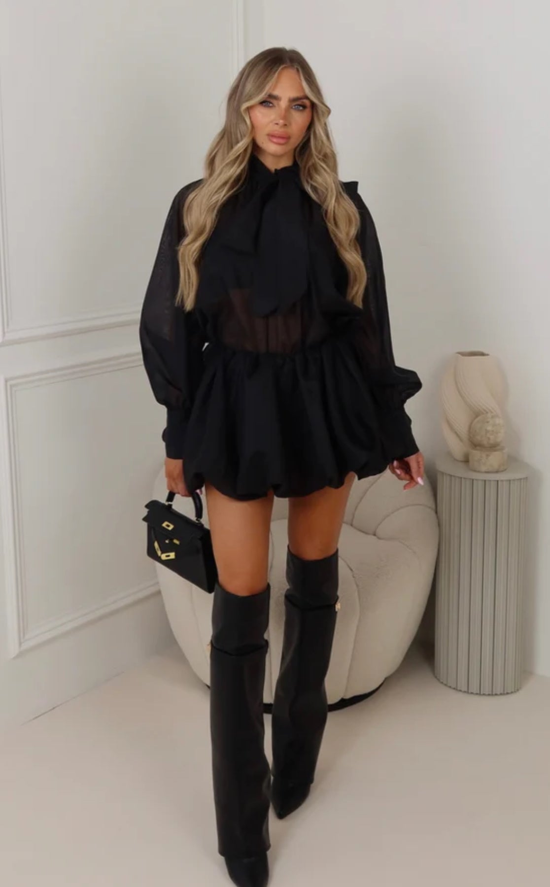 Outfit BIANCA Un look romantico e raffinato composto da blusa in organza trasparente con maxi fiocco sul collo e maniche ampie, abbinata a una minigonna a palloncino in tessuto leggero. Perfetto per outfit chic e femminili, ideale per eventi, aperitivi