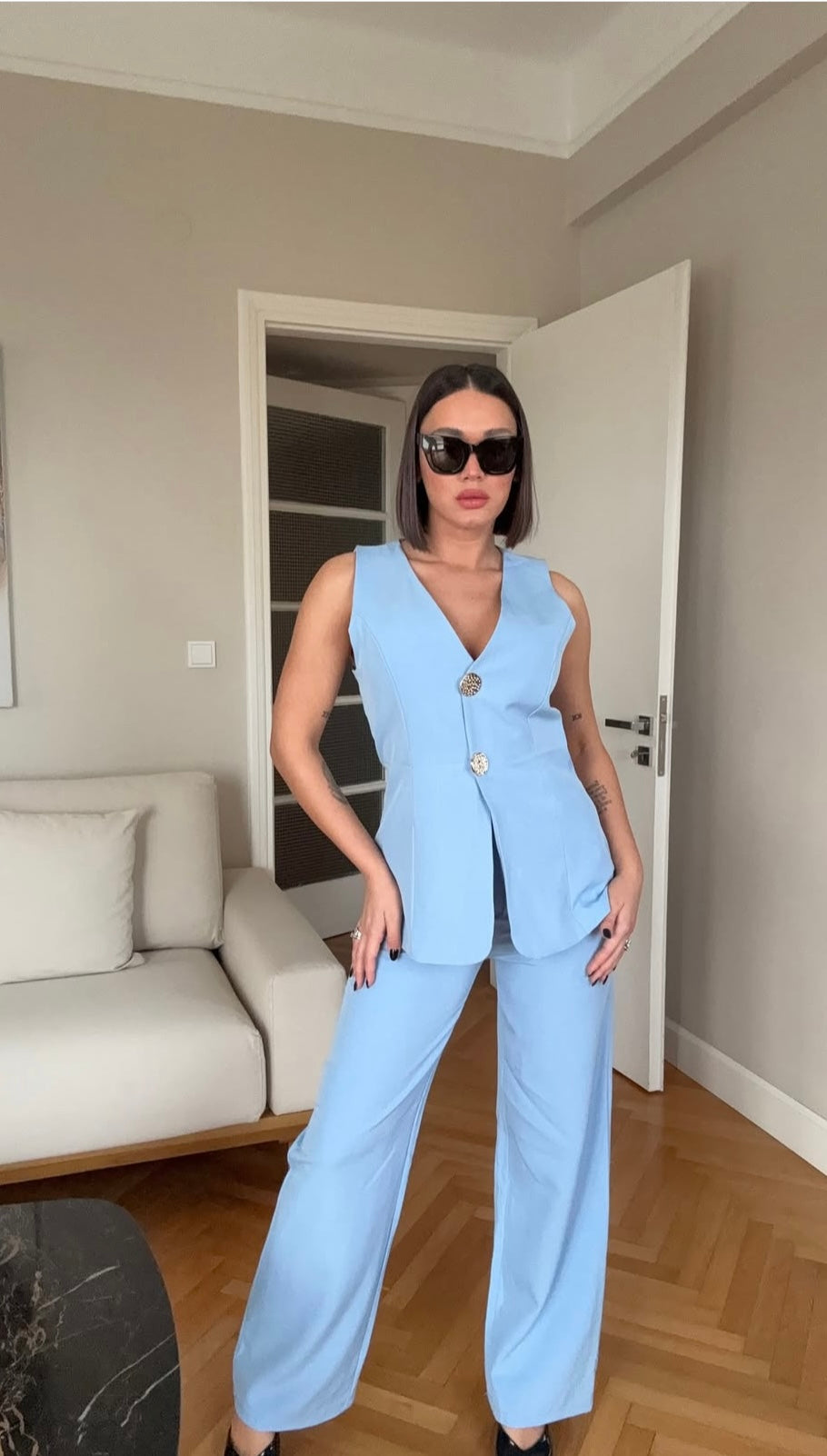 Tailleur ESTER elegante composto da un gilet smanicato e un paio di pantaloni a gamba larga Il gilet presenta due bottoni decorativi centrali dal design gioiello. I pantaloni sono a vita alta, con una vestibilità morbida e fluida