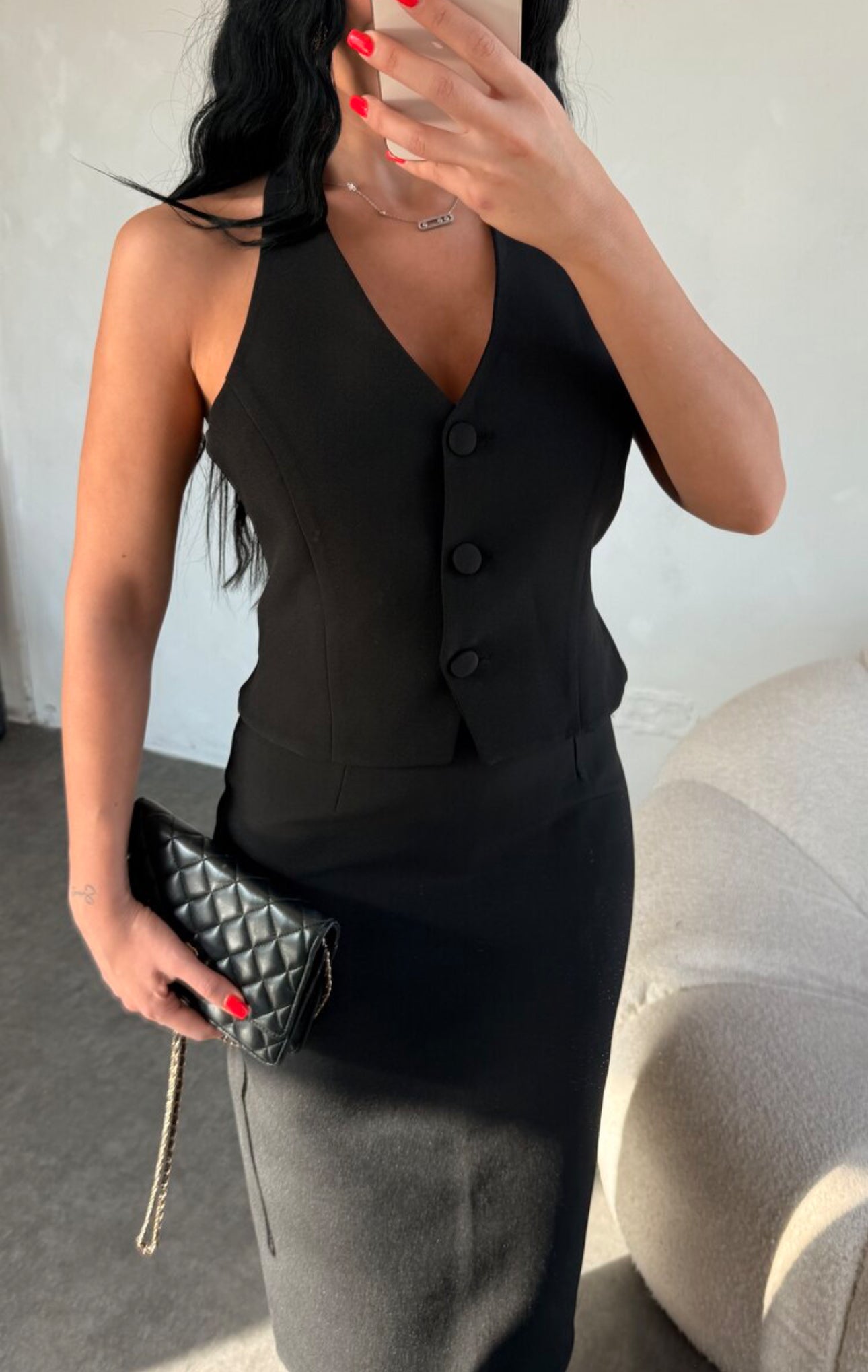Set ZAIRA indossa un elegante completo bianco composto da un top senza maniche con bottoni e scollo a V, insieme a una gonna a matita lunga fino alla caviglia. Il tessuto di alta qualità