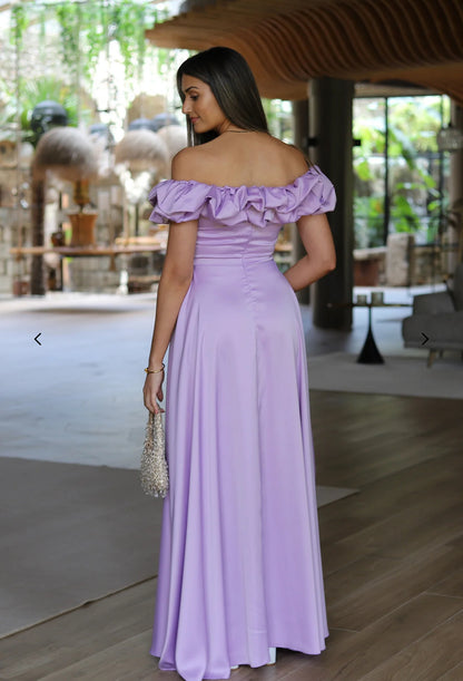 Abito MARYA Elegante abito off-shoulder con corpino arricciato a balze e ampia gonna con spacco laterale.