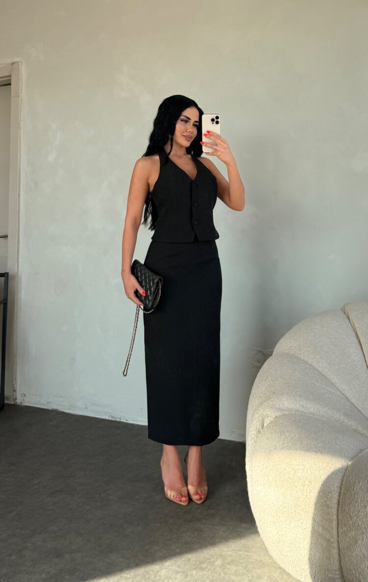 Set ZAIRA indossa un elegante completo bianco composto da un top senza maniche con bottoni e scollo a V, insieme a una gonna a matita lunga fino alla caviglia. Il tessuto di alta qualità