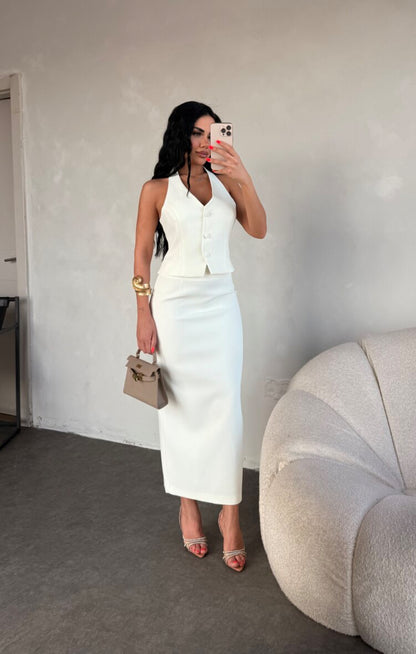 Set ZAIRA indossa un elegante completo bianco composto da un top senza maniche con bottoni e scollo a V, insieme a una gonna a matita lunga fino alla caviglia. Il tessuto di alta qualità