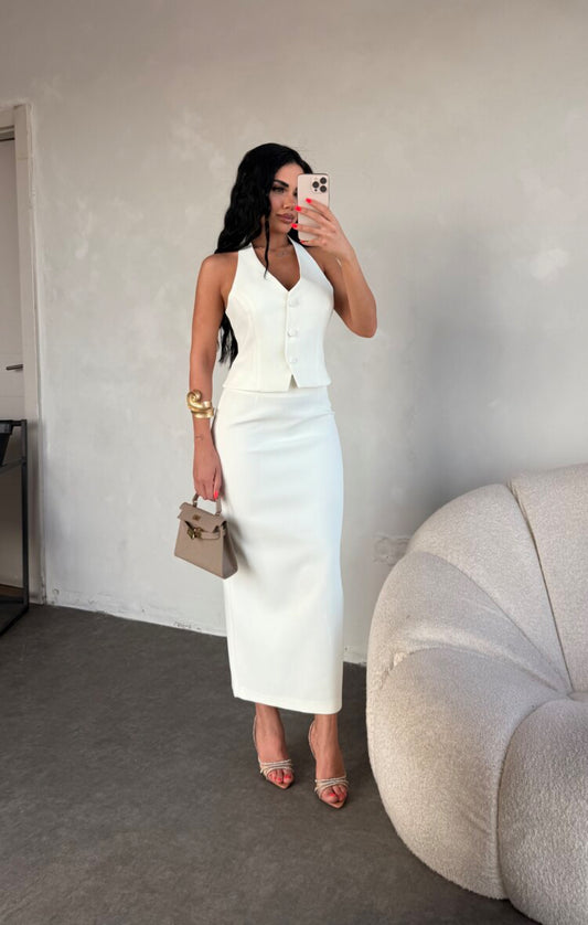 Set ZAIRA indossa un elegante completo bianco composto da un top senza maniche con bottoni e scollo a V, insieme a una gonna a matita lunga fino alla caviglia. Il tessuto di alta qualità