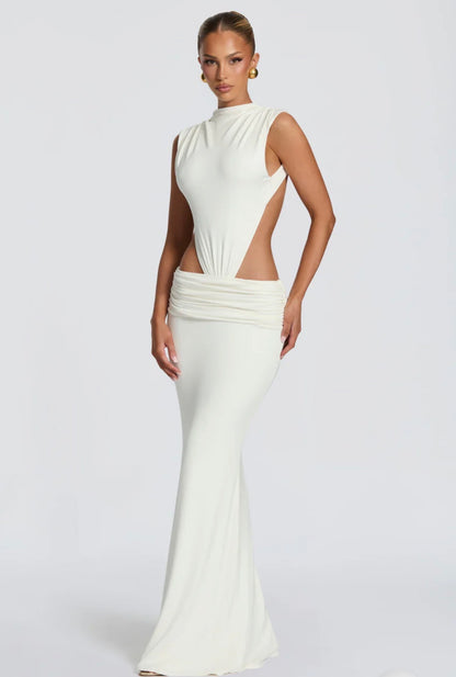Abito Sahara maxi aderente  con design cut-out laterale che scolpisce la silhouette. Il collo alto crea un raffinato contrasto con le ampie aperture sui fianchi e la schiena scoperta, per un effetto sensuale ma sofisticato.