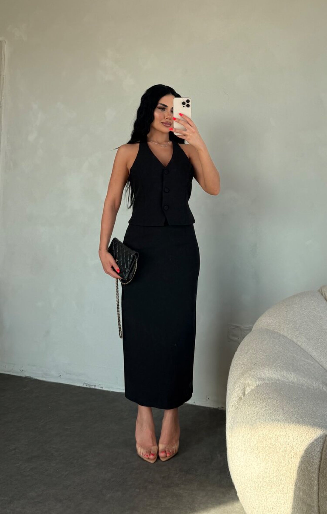 Set ZAIRA indossa un elegante completo bianco composto da un top senza maniche con bottoni e scollo a V, insieme a una gonna a matita lunga fino alla caviglia. Il tessuto di alta qualità
