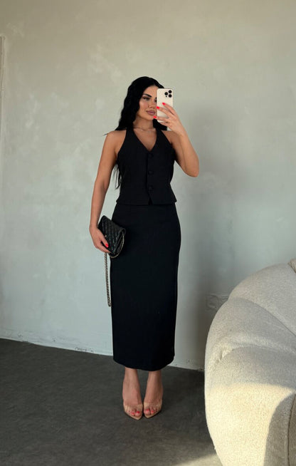 Set ZAIRA indossa un elegante completo bianco composto da un top senza maniche con bottoni e scollo a V, insieme a una gonna a matita lunga fino alla caviglia. Il tessuto di alta qualità