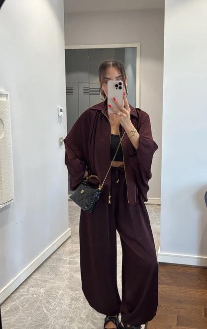 Coordinato PRISCILLA Completo elegante e versatile in tessuto satinato composto da giacca leggera oversize con zip e pantaloni ampi a vita alta con coulisse. Perfetto per look chic e confortevoli, dal giorno alla sera.