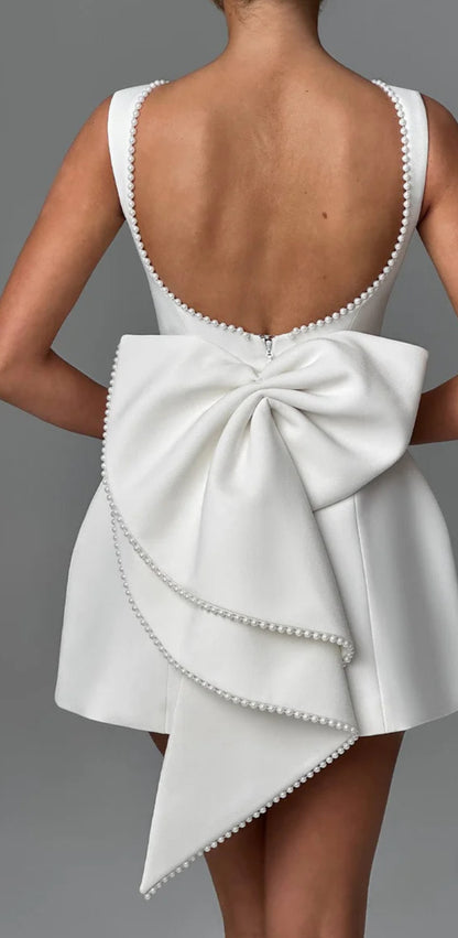 Mini Dress ALESSIA caratterizzato da un design sofisticato e femminile. Presenta una scollatura profonda sulla schiena, impreziosita da un bordo di perline che segue il profilo delle spalline e il décolleté posteriore…