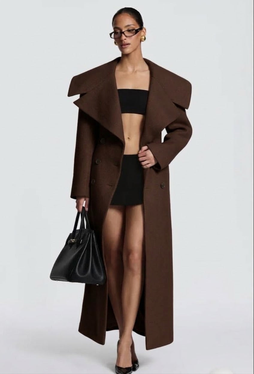 Cappotto Lungo Sartoriale con Maximantellina Un capospalla scenografico e di classe che ridefinisce l'eleganza invernale. Caratterizzato da un'ampia mantellina sulle spalle e una silhouette clessidra accentuata dal punto vita segnato.