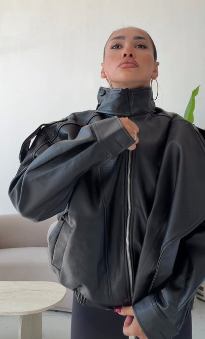 Giacca Biker Oversize in pelle Caratterizzata da una silhouette strutturata con spalle scese e un collo alto avvolgente con cinturino, è il capo spalla perfetto per completare i tuoi outfit streetwear ed eleganti con un tocco audace.