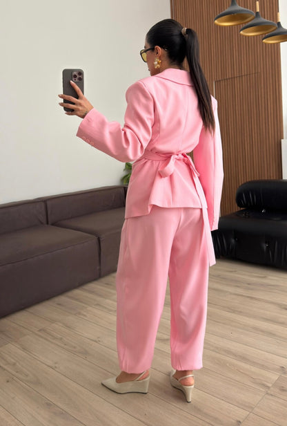 Tailleur Samantha”in promo” composto da giacca sartoriale con spalle strutturate e chiusura incrociata. La cintura integrata con bottoni decorativi stringe il punto vita valorizzando la silhouette e creando un elegante effetto corsetto l pantalone fluido