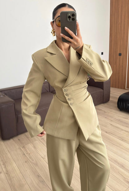 Tailleur Samantha”in promo” composto da giacca sartoriale con spalle strutturate e chiusura incrociata. La cintura integrata con bottoni decorativi stringe il punto vita valorizzando la silhouette e creando un elegante effetto corsetto l pantalone fluido