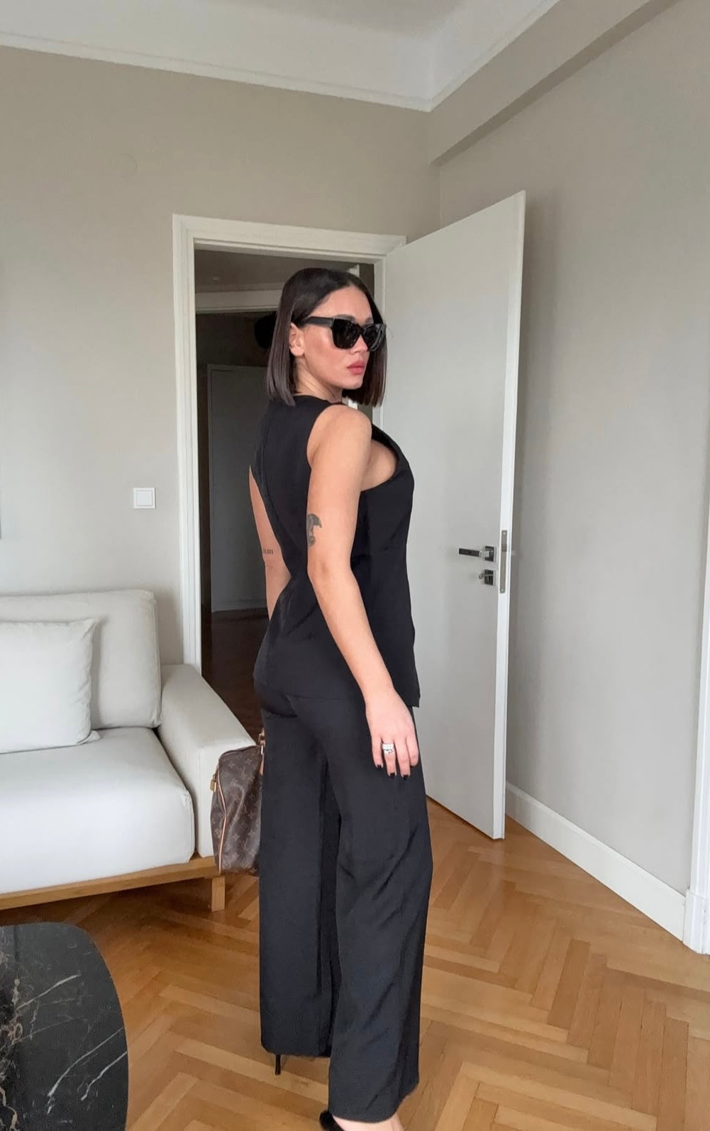 Tailleur ESTER elegante composto da un gilet smanicato e un paio di pantaloni a gamba larga  Il gilet presenta due bottoni decorativi centrali dal design gioiello. I pantaloni sono a vita alta, con una vestibilità morbida e fluida