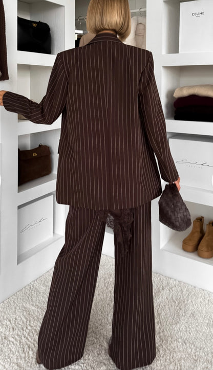 Tailleur Erika sofisticato dal carattere deciso, perfetto per chi ama un’eleganza contemporanea con un tocco sensuale. Il set è composto da blazer doppio petto gessato con top in pizzo e pantalone coordinato a gamba ampia