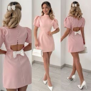 Mini Dress ALICE e sofisticato con maniche corte a sbuffo e una chiusura posteriore con bottoni  rivestiti di perle, che aggiungono un tocco raffinato. La parte posteriore ha un'apertura che lascia intravedere la schiena, valorizzata da un fiocco