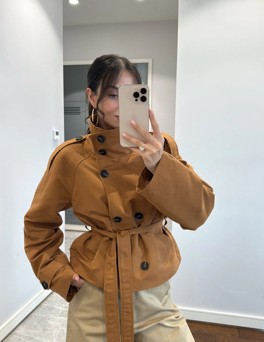 Trench MARCELLA in promo Elegante trench corto con cintura regolabile e bottoni a contrasto. Design moderno e versatile, perfetto per look casual o raffinati.