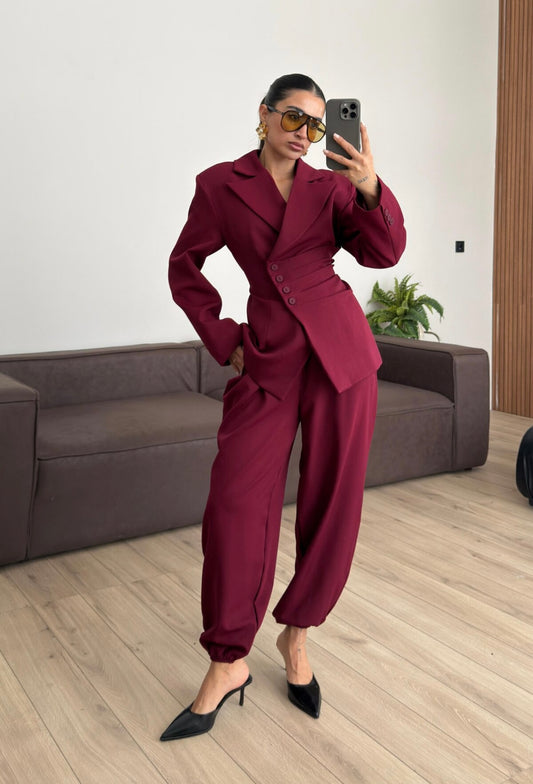 Tailleur Samantha”in promo” composto da giacca sartoriale con spalle strutturate e chiusura incrociata. La cintura integrata con bottoni decorativi stringe il punto vita valorizzando la silhouette e creando un elegante effetto corsetto l pantalone fluido