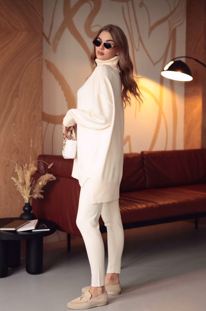 Coordinato ALBA indossa un coordinato in stile minimal e raffinato.
L'outfit è composto da un maxi maglione a collo alto in maglia con un design oversize e spacchetti laterali. È abbinato a pantaloni slim fit in coordinato