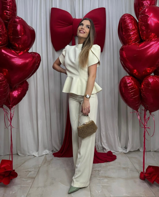 Tailleur ROSSELLA  La giacca presenta maniche corte a sbuffo, una fila di bottoni rivestiti lungo la schiena e un raffinato dettaglio cut-out impreziosito da un fiocco decorativo e un delicato i pantaloni sono a gamba larga, cadono morbidi ed eleganti