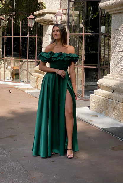 Abito MARYA Elegante abito off-shoulder con corpino arricciato a balze e ampia gonna con spacco laterale.