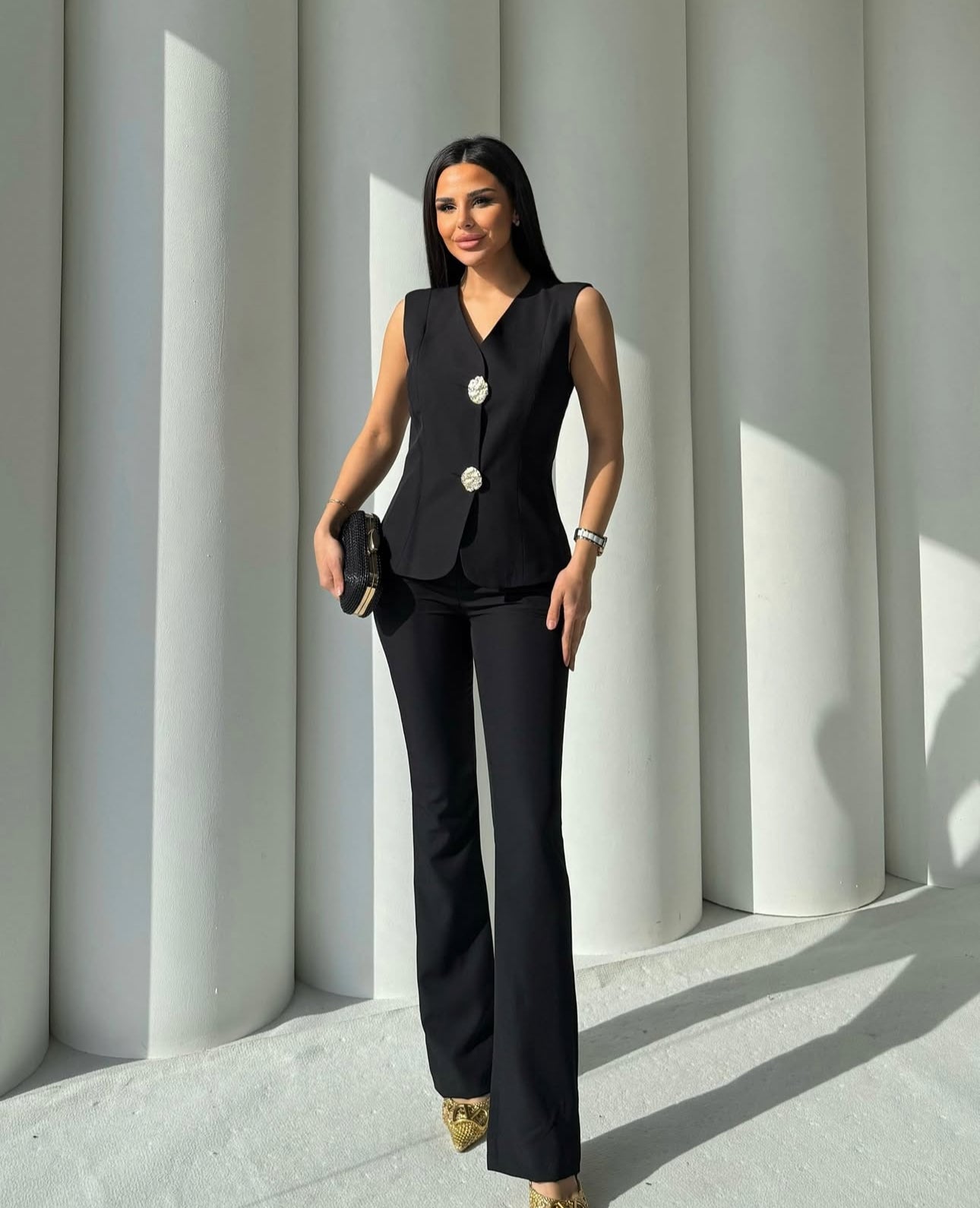 Set cord PERLA elegante composto da un gilet smanicato e un paio di pantaloni a gamba larga  Il gilet presenta due bottoni decorativi centrali dal design gioiello. I pantaloni sono a vita alta, con una vestibilità morbida e fluida