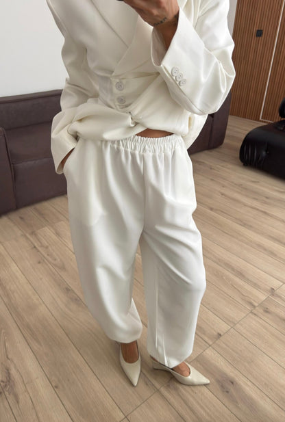 Tailleur Samantha”in promo” composto da giacca sartoriale con spalle strutturate e chiusura incrociata. La cintura integrata con bottoni decorativi stringe il punto vita valorizzando la silhouette e creando un elegante effetto corsetto l pantalone fluido