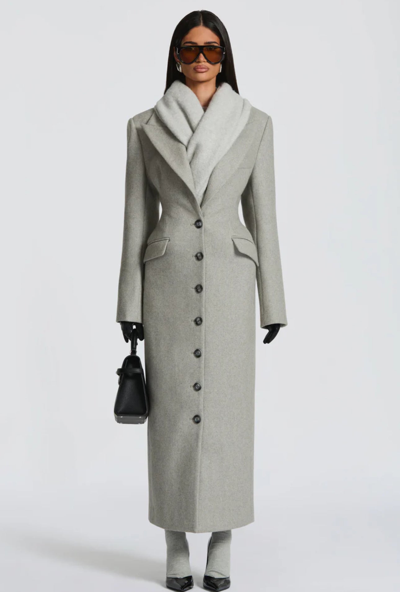 Cappotto ANGELICA lungo grigio in lana, con bottoni frontali e maxi revers a scialle. La linea dritta e sartoriale slancia la figura, mentre il colletto ampio aggiunge un tocco sofisticato. Perfetto per look invernali raffinati, dal giorno alla sera.