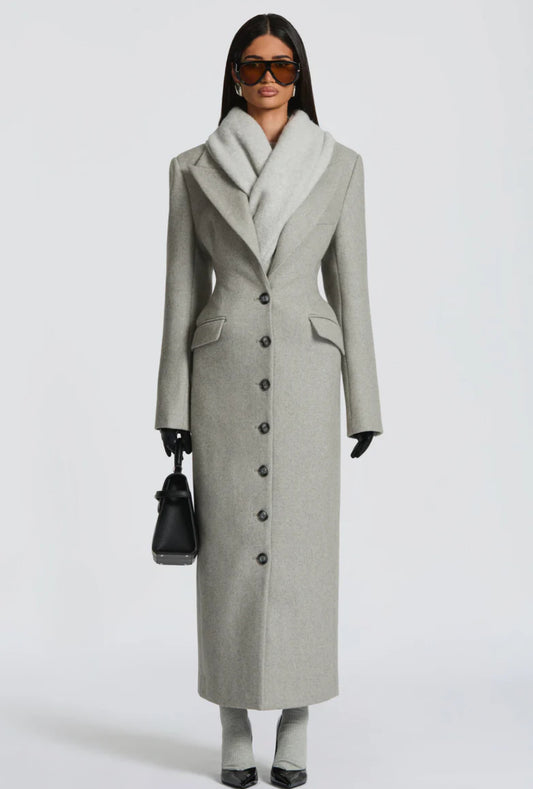 Cappotto ANGELICA lungo grigio in lana, con bottoni frontali e maxi revers a scialle. La linea dritta e sartoriale slancia la figura, mentre il colletto ampio aggiunge un tocco sofisticato. Perfetto per look invernali raffinati, dal giorno alla sera.