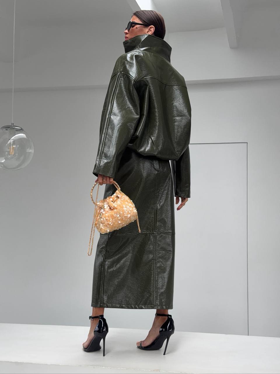 Co-ord Set in Similpelle Lucida Effect Noir
L'audacia incontra l'eleganza contemporanea. Eleva il tuo guardaroba con questo esclusivo coordinato a due pezzi, composto da una giacca bomber dallo stile urban-chic e una gonna midi dalla silhouette affusolata