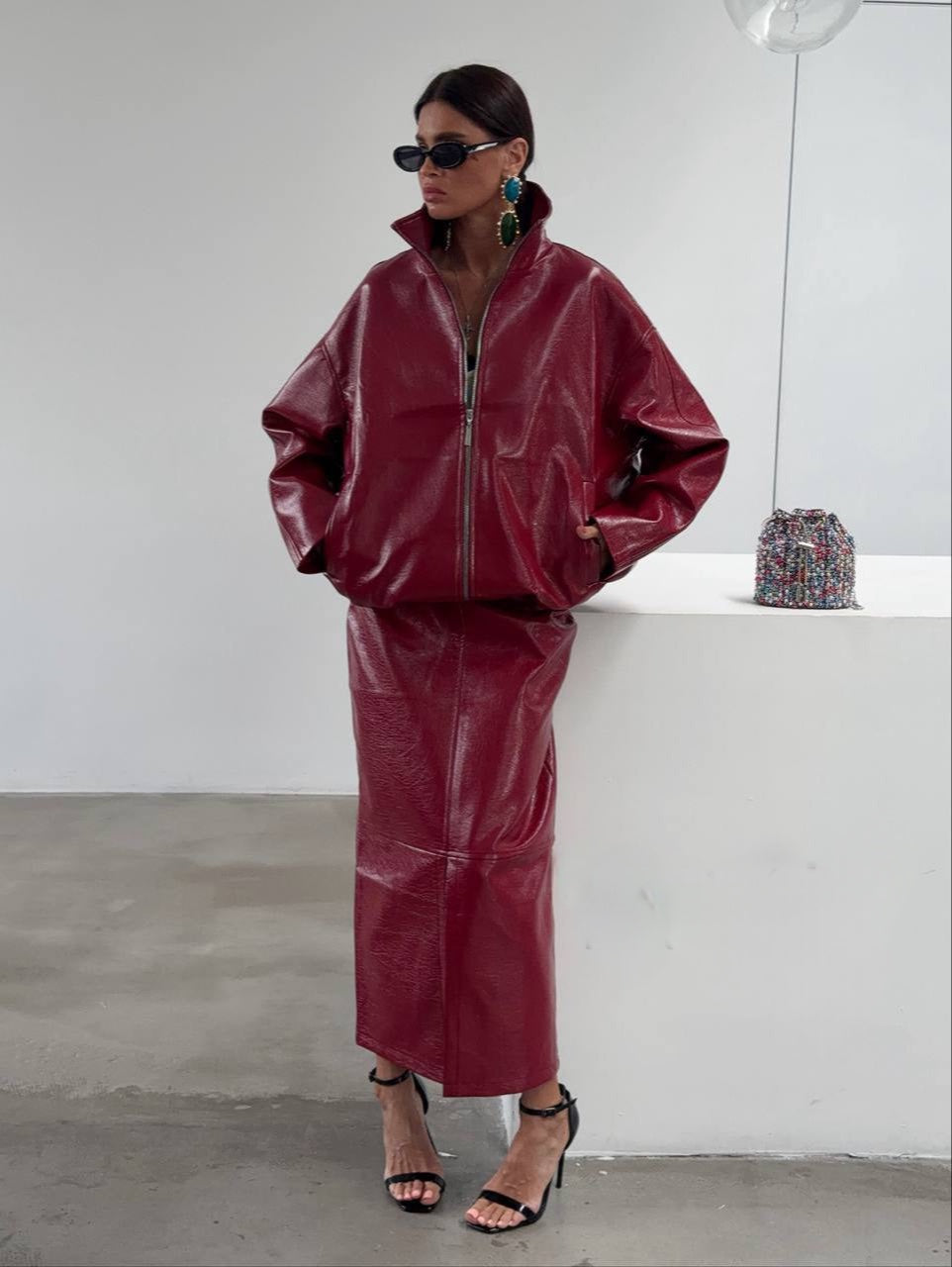 Co-ord Set in Similpelle Lucida Effect Noir
L'audacia incontra l'eleganza contemporanea. Eleva il tuo guardaroba con questo esclusivo coordinato a due pezzi, composto da una giacca bomber dallo stile urban-chic e una gonna midi dalla silhouette affusolata