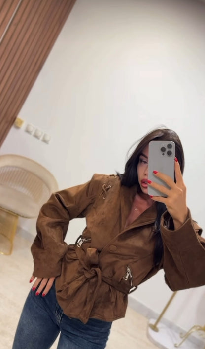 Giacca FIAMMA Giacca dal taglio moderno in morbido suede marrone, caratterizzata da dettagli con lacci sulle spalle e zip laterali. La cintura in vita sottolinea la silhouette, rendendola un capo versatile
