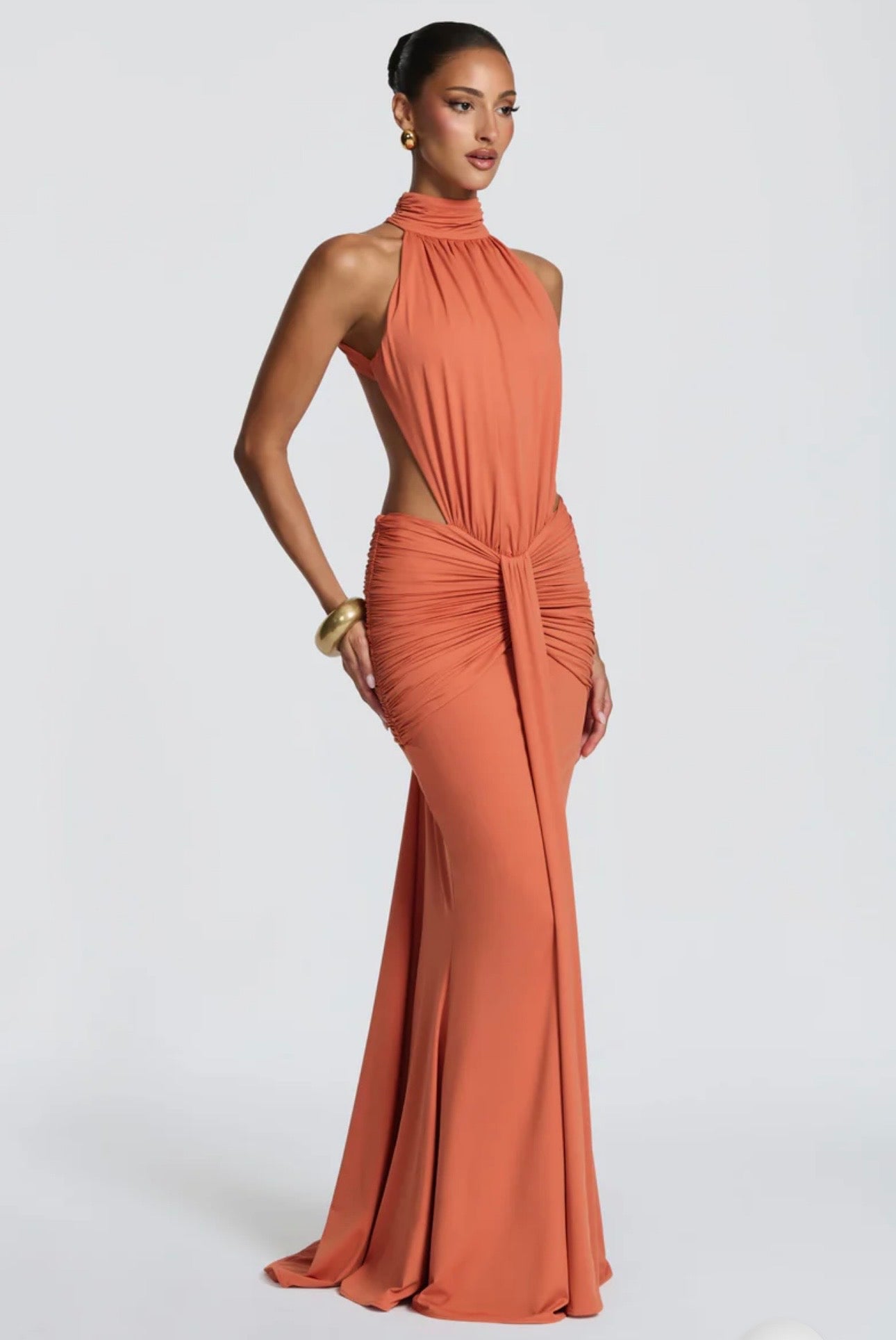 Abito Sofia Caratterizzato da una silhouette a sirena che valorizza le forme, questo modello unisce un sofisticato collo alto a un audace gioco di drappeggi e intagli cut-out sui fianchi.