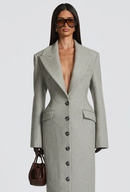 Cappotto ANGELICA lungo grigio in lana, con bottoni frontali e maxi revers a scialle. La linea dritta e sartoriale slancia la figura, mentre il colletto ampio aggiunge un tocco sofisticato. Perfetto per look invernali raffinati, dal giorno alla sera.