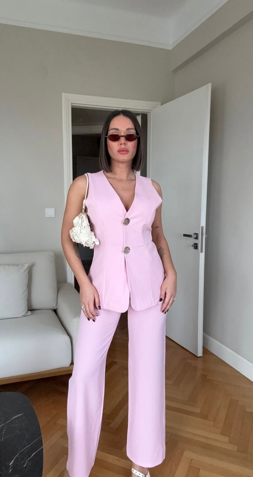 Tailleur ESTER elegante composto da un gilet smanicato e un paio di pantaloni a gamba larga  Il gilet presenta due bottoni decorativi centrali dal design gioiello. I pantaloni sono a vita alta, con una vestibilità morbida e fluida