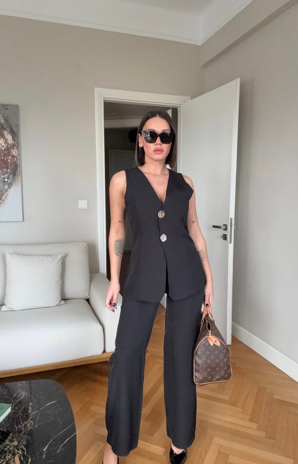 Tailleur ESTER elegante composto da un gilet smanicato e un paio di pantaloni a gamba larga  Il gilet presenta due bottoni decorativi centrali dal design gioiello. I pantaloni sono a vita alta, con una vestibilità morbida e fluida