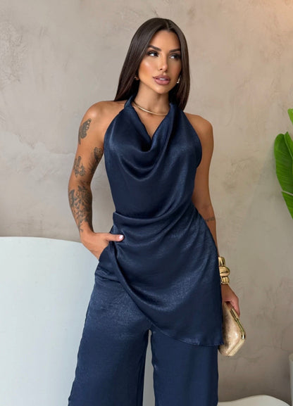 Coordinato Barbara Il set è composto di seta satinata da un top con scollo a cappuccio e schiena scoperta che valorizza la silhouette, abbinato a un pantalone a palazzo fluido che slancia la figura ad ogni passo.