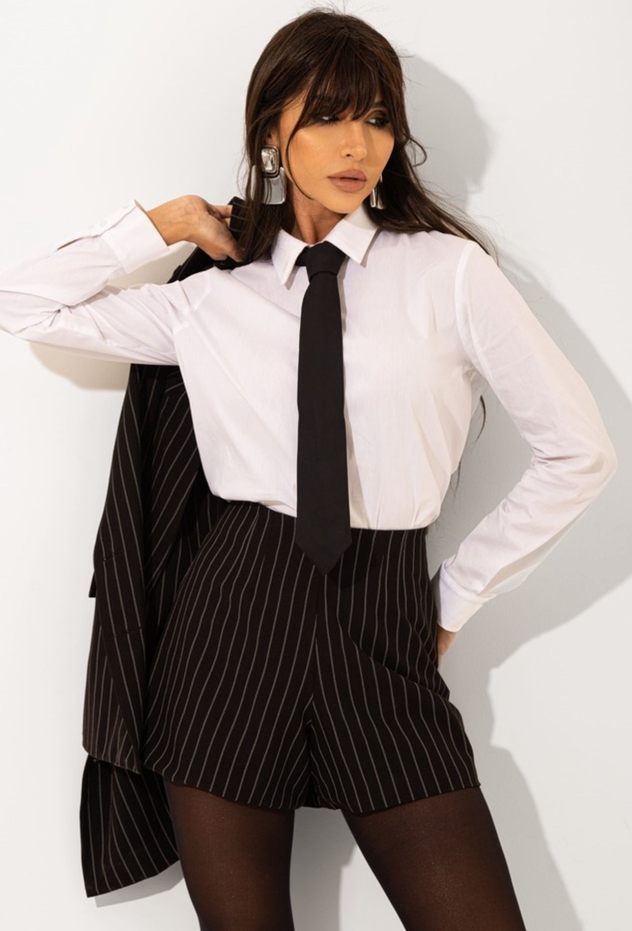 Tailleur Madison outfit dal carattere deciso e sofisticato composto da blazer gessato dal taglio sartoriale e shorts coordinati camicia e cravatta, il design elegante incontra uno stile moderno e urbano, perfetto per creare look raffinati