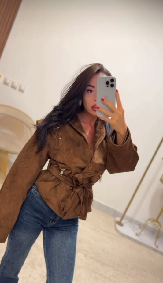 Giacca FIAMMA Giacca dal taglio moderno in morbido suede marrone, caratterizzata da dettagli con lacci sulle spalle e zip laterali. La cintura in vita sottolinea la silhouette, rendendola un capo versatile