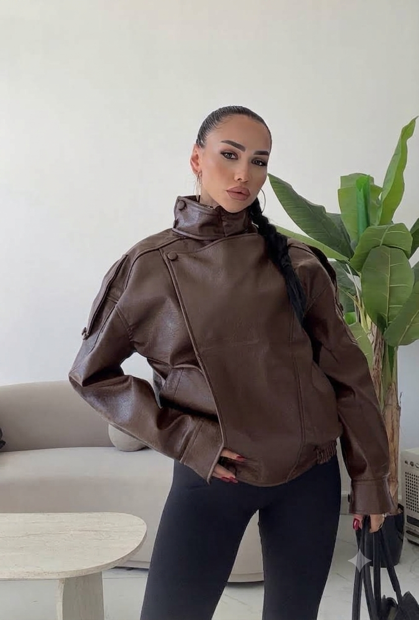 Giacca Biker Oversize in pelle Caratterizzata da una silhouette strutturata con spalle scese e un collo alto avvolgente con cinturino, è il capo spalla perfetto per completare i tuoi outfit streetwear ed eleganti con un tocco audace.