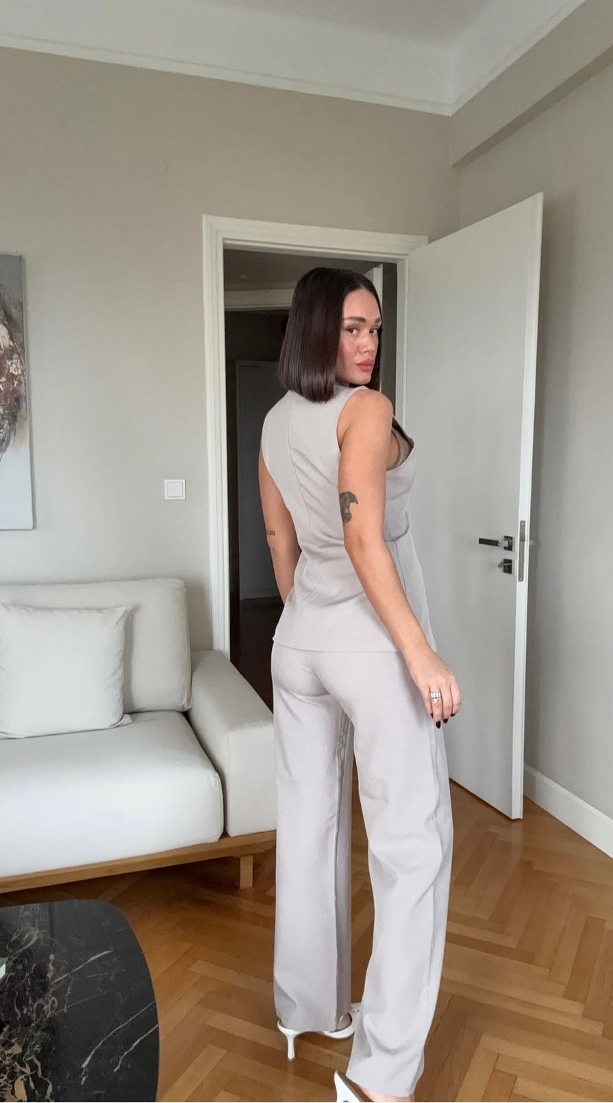 Tailleur ESTER elegante composto da un gilet smanicato e un paio di pantaloni a gamba larga  Il gilet presenta due bottoni decorativi centrali dal design gioiello. I pantaloni sono a vita alta, con una vestibilità morbida e fluida