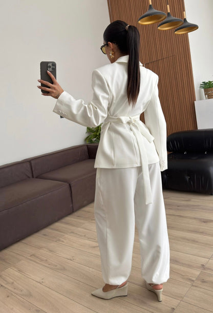 Tailleur Samantha”in promo” composto da giacca sartoriale con spalle strutturate e chiusura incrociata. La cintura integrata con bottoni decorativi stringe il punto vita valorizzando la silhouette e creando un elegante effetto corsetto l pantalone fluido