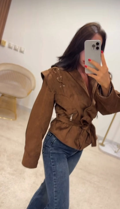 Giacca FIAMMA Giacca dal taglio moderno in morbido suede marrone, caratterizzata da dettagli con lacci sulle spalle e zip laterali. La cintura in vita sottolinea la silhouette, rendendola un capo versatile