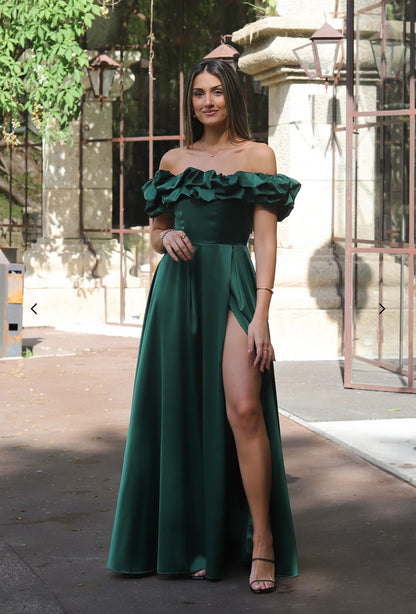 Abito MARYA Elegante abito off-shoulder con corpino arricciato a balze e ampia gonna con spacco laterale.