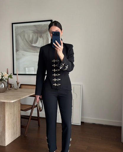 Tailleur Rosella caratterizzato da dettagli in metallo argentato con fibbie decorative sul davanti della giacca e sulla caviglia del pantalone.