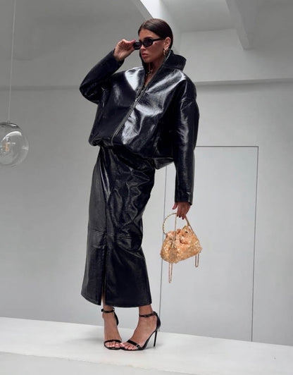 Co-ord Set in Similpelle Lucida Effect Noir
L'audacia incontra l'eleganza contemporanea. Eleva il tuo guardaroba con questo esclusivo coordinato a due pezzi, composto da una giacca bomber dallo stile urban-chic e una gonna midi dalla silhouette affusolata