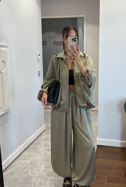 Coordinato PRISCILLA Completo elegante e versatile in tessuto satinato composto da giacca leggera oversize con zip e pantaloni ampi a vita alta con coulisse. Perfetto per look chic e confortevoli, dal giorno alla sera.