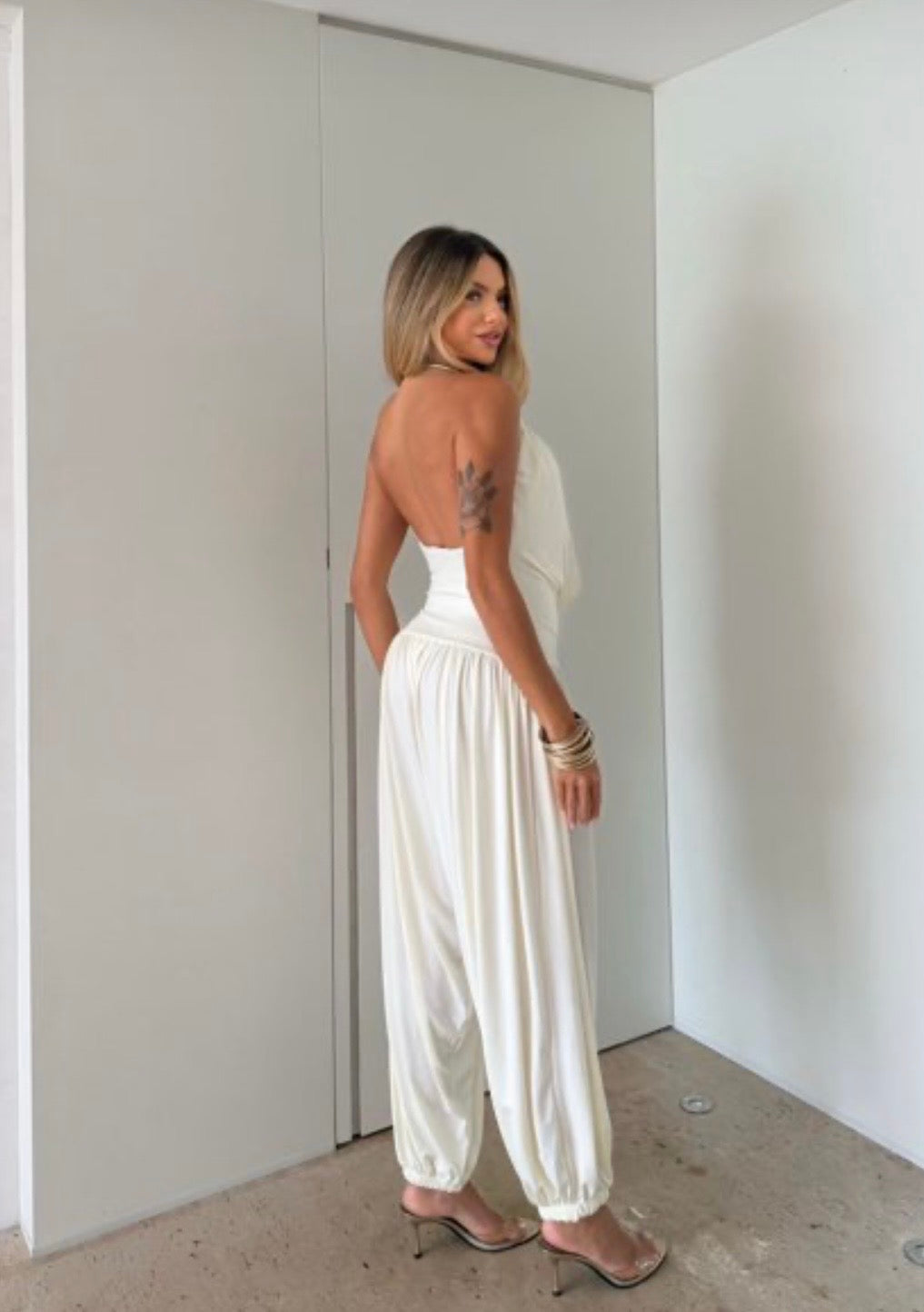 Jumpsuite Gioia Un'eleganza senza tempo racchiusa in una silhouette fluida e sensuale. La Tuta Drappeggiata è pensata per la donna che sa come catturare ogni sguardo senza sforzo.