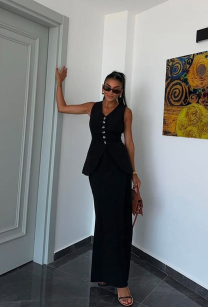Tailleur ANTONELLA elegante in stile sartoriale è composto da un gilet senza maniche con scollo a V e chiusura a bottoni frontali. La gonna lunga e dritta si abbina perfettamente al gilet, creando un look sofisticato e minimalista