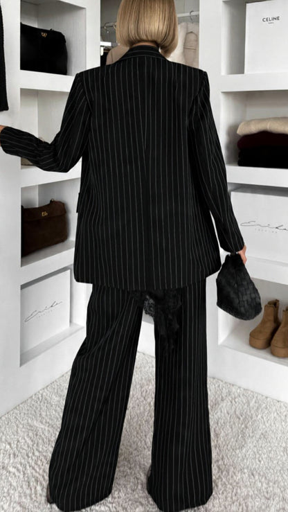 Tailleur Erika sofisticato dal carattere deciso, perfetto per chi ama un’eleganza contemporanea con un tocco sensuale. Il set è composto da blazer doppio petto gessato con top in pizzo e pantalone coordinato a gamba ampia